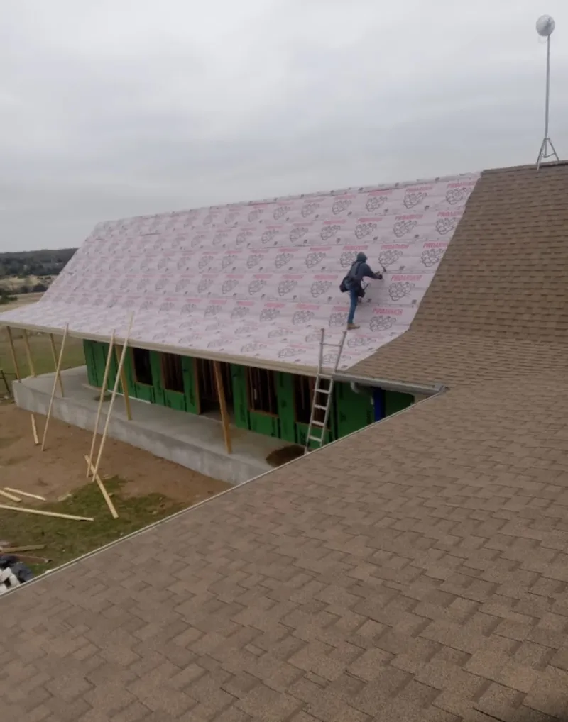 Worker preparing underlayment for a metal roof installation in Hidalgo